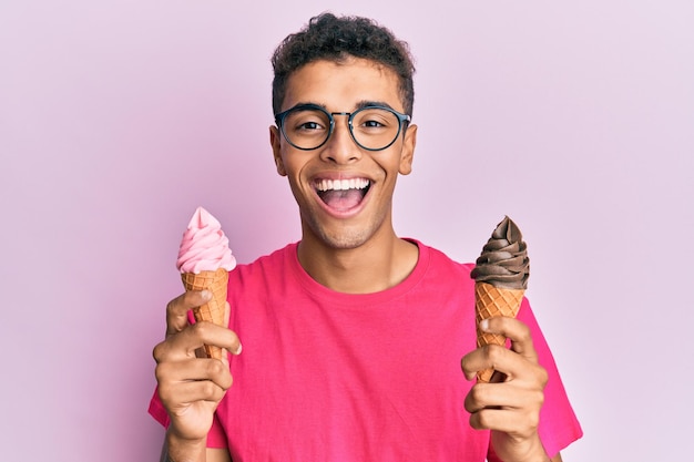 Foto jonge knappe afro-amerikaanse man die ijsjes vasthoudt glimlacht en hard lacht luid omdat grappige gekke grap