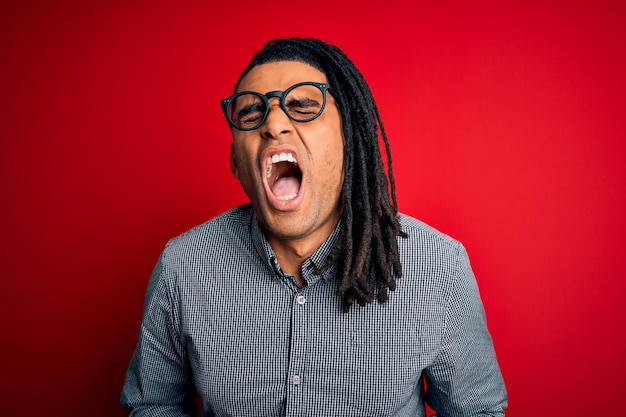 Jonge knappe afro-amerikaanse man met dreadlocks in casual shirt en bril met hand op buik omdat misselijkheid pijnlijke ziekte onwel voelen Ache concept