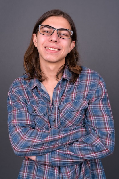 jonge knappe androgyne hipster man met lang haar tegen grijze muur