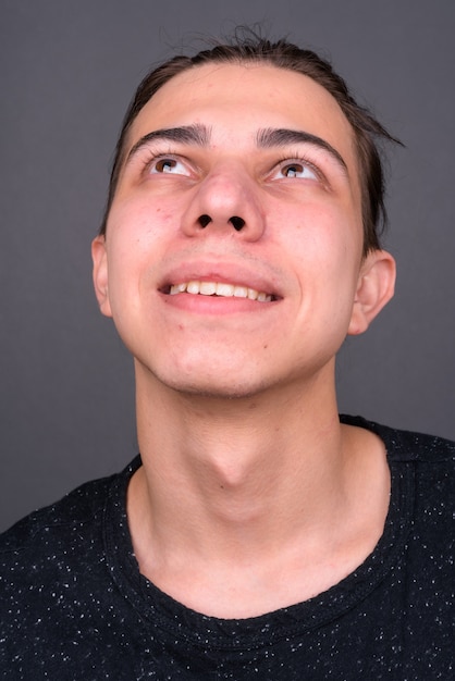 jonge knappe androgyne man met lang haar tegen grijze muur