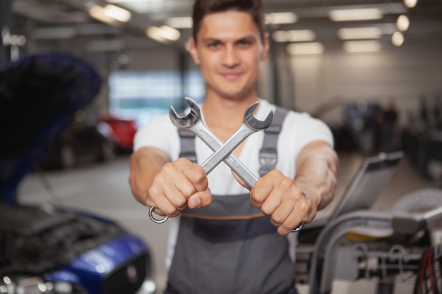 Jonge knappe autowerktuigkundige die voertuig in zijn garage herstelt