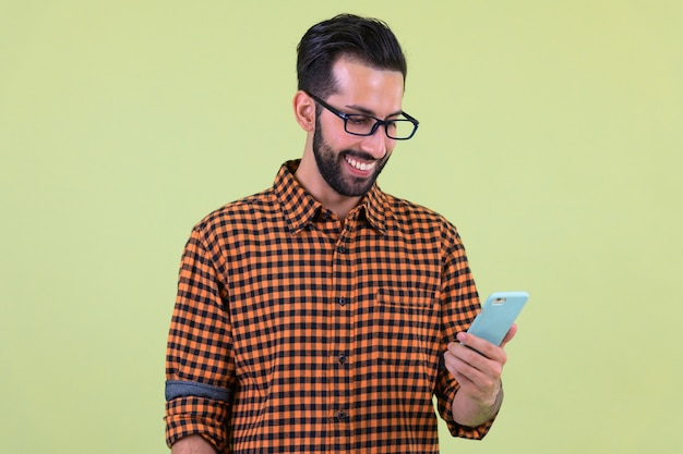 jonge knappe bebaarde Perzische hipster man tegen gekleurde muur