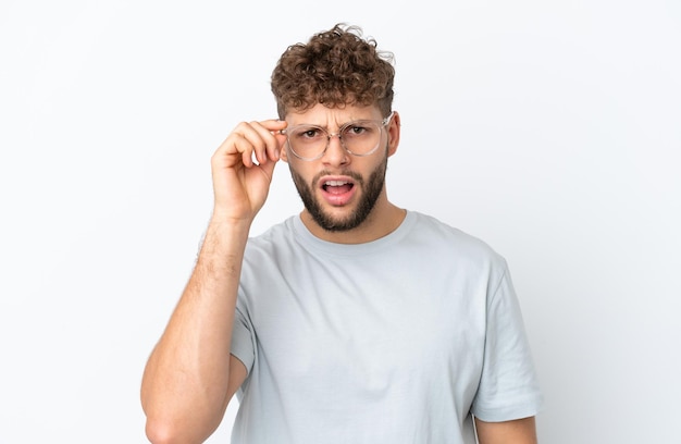 Jonge knappe blanke man geïsoleerd op een witte achtergrond Met een bril en gefrustreerde expressie