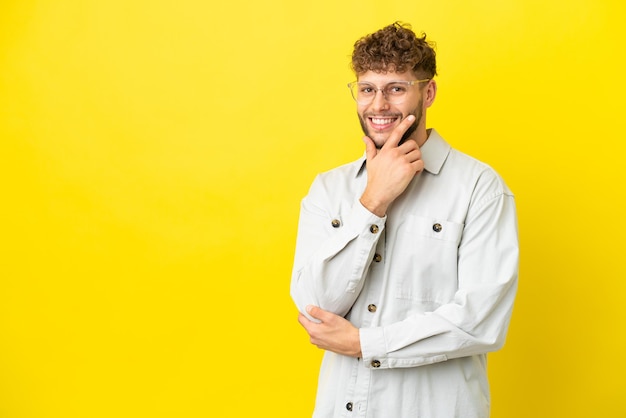 Jonge knappe blanke man geïsoleerd op gele achtergrond gelukkig en glimlachend