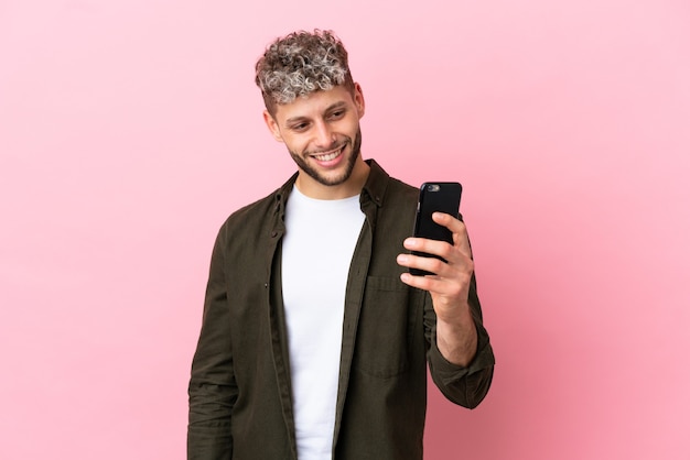 Jonge knappe blanke man geïsoleerd op roze achtergrond die een selfie maakt