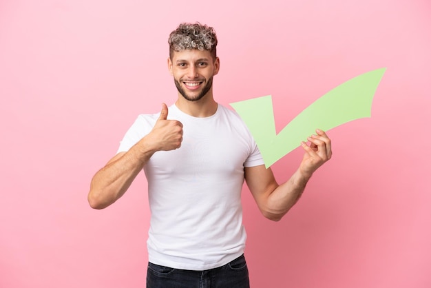 Jonge knappe blanke man geïsoleerd op roze achtergrond met een vinkje met duim omhoog