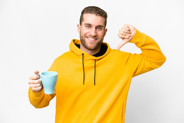 Jonge knappe blonde man met kopje koffie over geïsoleerde achtergrond trots en zelfvoldaan