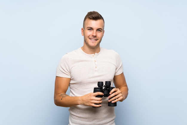 Jonge knappe blonde man met zwarte verrekijker