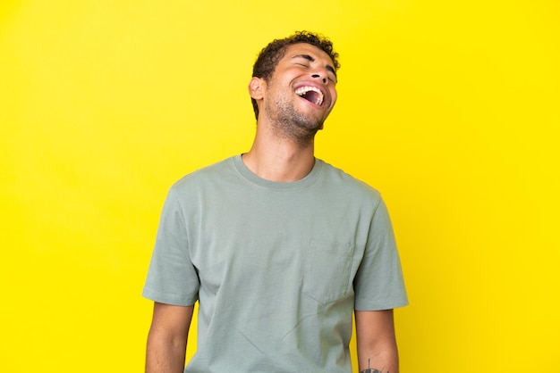 Jonge knappe Braziliaanse man geïsoleerd op gele achtergrond lachen