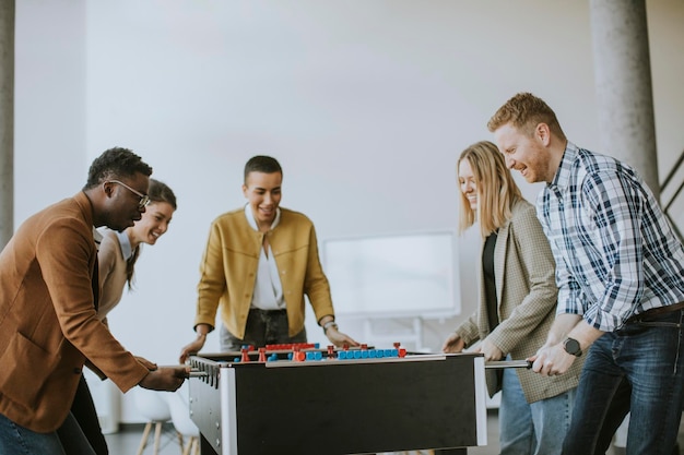 Jonge knappe casual multi-etnische zakenmensen die tafelvoetbal spelen en ontspannen op kantoor