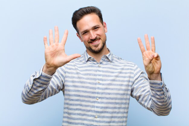 Jonge knappe en mens die vriendelijk glimlachen kijken, tonend nummer acht of achtste met voorwaartse hand, aftellend