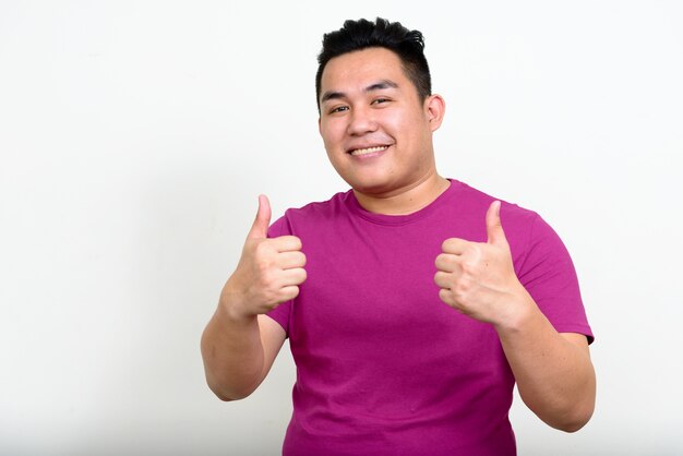 jonge knappe Filipijnse man met overgewicht tegen een witte muur