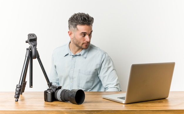 Jonge knappe fotografie leraar kijkt opzij lachend, vrolijk en aangenaam.