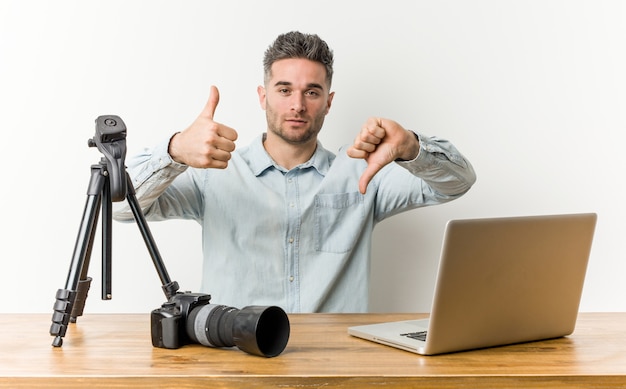 Jonge knappe fotografie leraar tonen duimen omhoog en duimen naar beneden, moeilijk kiezen