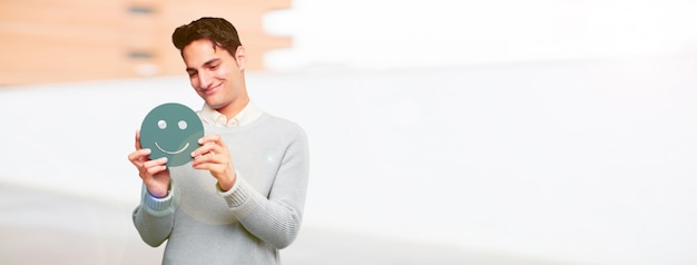 Jonge knappe gebruinde man met een smiley emoticon