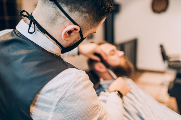 Jonge knappe hipste man die een kapperszaak bezoekt. Trendy en stijlvolle baard styling en snit.