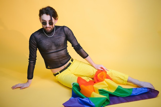 Jonge knappe homoseksuele man op een gekleurde achtergrond in het studio LGBT-concept