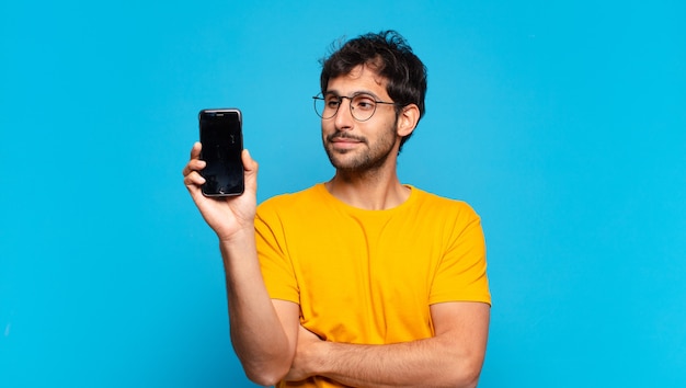 Jonge knappe Indiase man gelukkige uitdrukking en met een mobiele telefoon