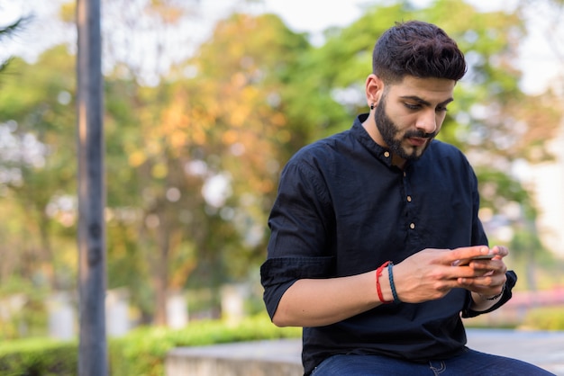 Jonge knappe Indiase man met behulp van mobiele telefoon