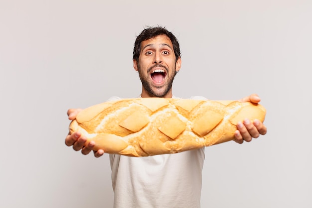 Jonge knappe indiase man verraste uitdrukking en houdt een brood vast