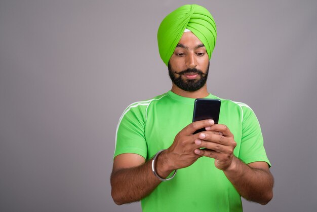 Jonge knappe Indiase Sikh man texting met mobiele telefoon