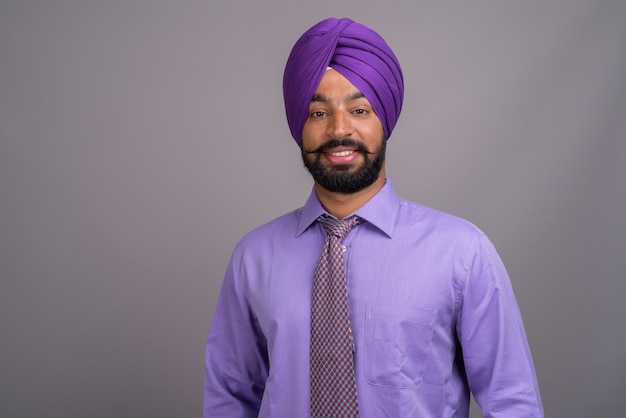 Jonge knappe Indiase Sikh zakenman tulband op grijs dragen