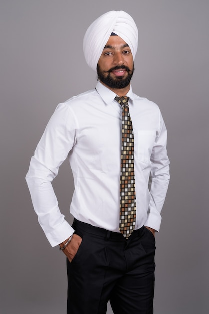 Jonge knappe Indiase Sikh zakenman tulband op grijs dragen