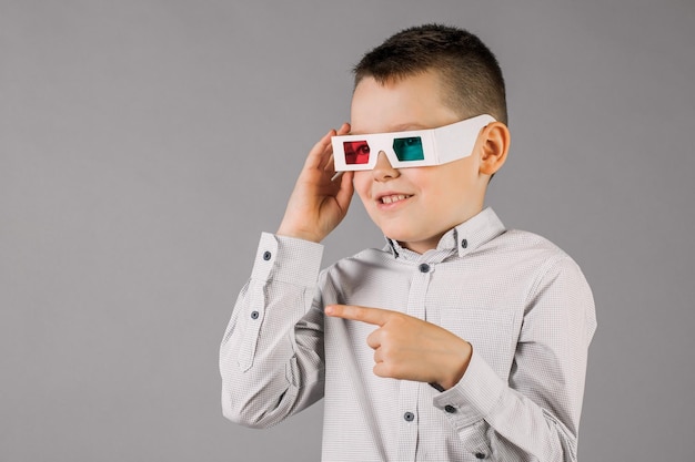 Jonge knappe jongen met 3D-bril op grijze achtergrond in Studio