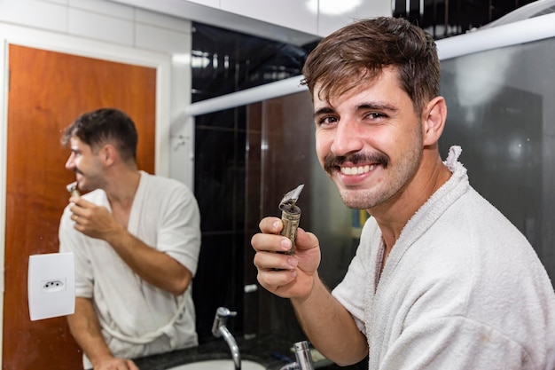 Jonge knappe jongen scheren in de badkamer met een scheermes