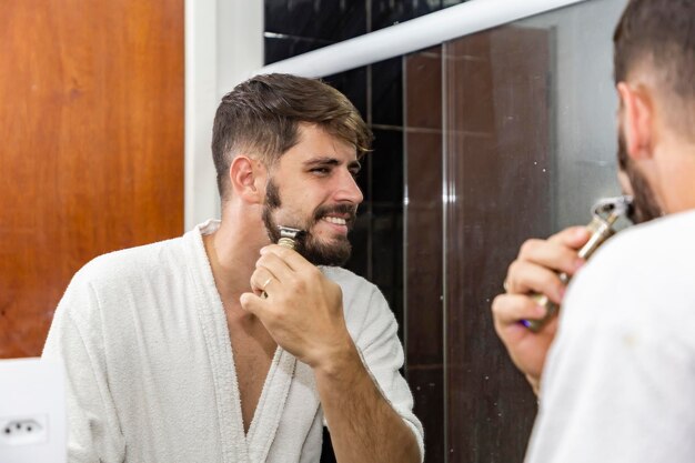 Jonge knappe jongen scheren in de badkamer