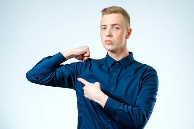 Jonge knappe jongen wijzend op zijn biceps