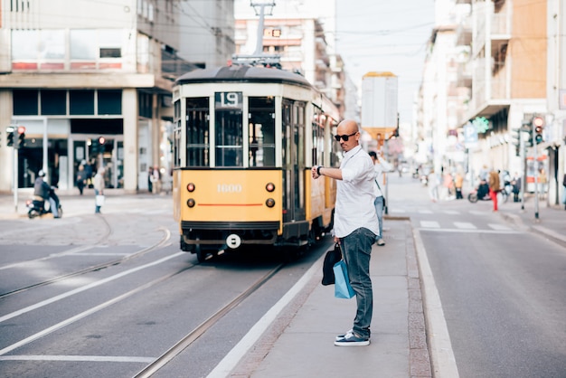 Foto jonge knappe kaukasische kale bedrijfsmens die op de tram wacht