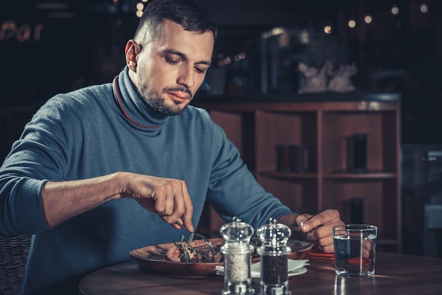 Jonge knappe man aan het eten in het restaurant