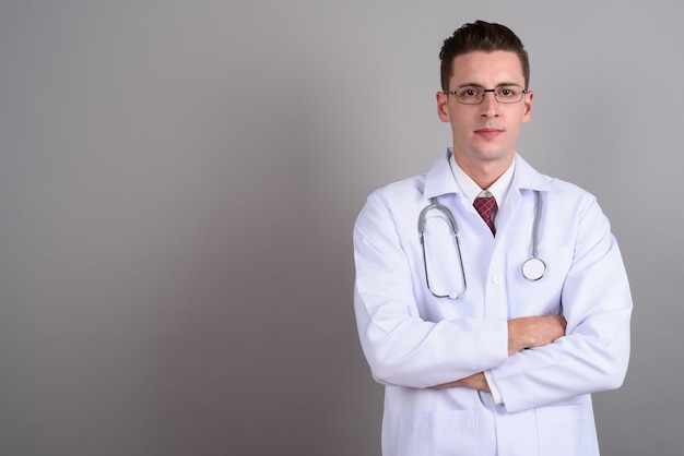 jonge knappe man arts bril dragen op grijs