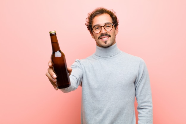 Jonge knappe man dansen met een biertje tegen roze platte muur