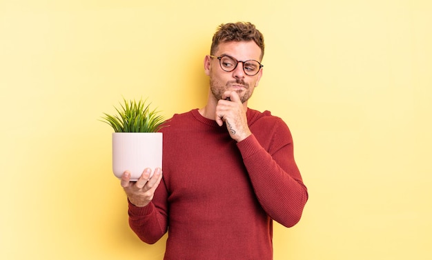 Jonge knappe man denkt, voelt zich twijfelachtig en verward. decoratief plantenconcept