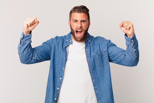 Jonge knappe man die agressief schreeuwt met een boze uitdrukking