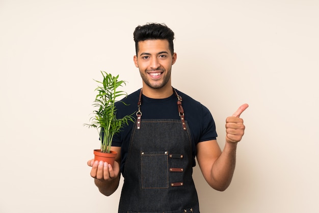 Jonge knappe man die een bloempot en met duim omhoog