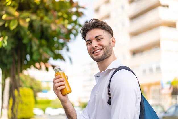 Jonge knappe man die een jus d'orange vasthoudt en veel glimlacht