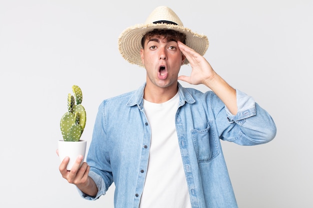 Jonge knappe man die er blij, verbaasd en verrast uitziet. boer met een decoratieve cactus