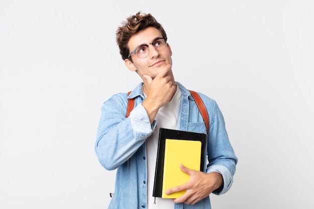 Jonge knappe man die gelukkig lacht en dagdroomt of twijfelt. universitair studentenconcept