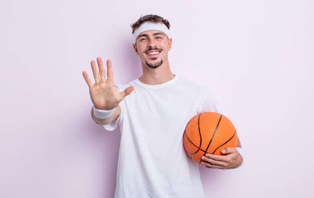 Jonge knappe man die lacht en er vriendelijk uitziet, met nummer vijf. basketbal concept