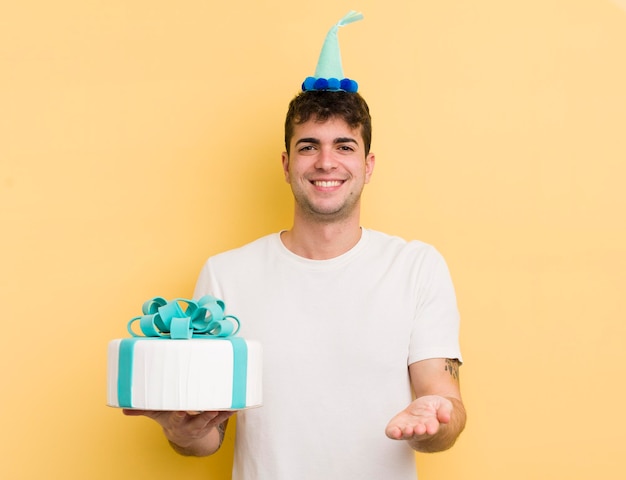 Jonge knappe man die vrolijk lacht met vriendelijk en een concept verjaardagsconcept aanbiedt en toont
