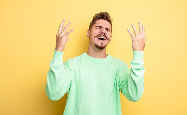 jonge knappe man die woedend schreeuwt, zich gestrest en geïrriteerd voelt met zijn handen in de lucht en zegt waarom ik. vreemd snorconcept