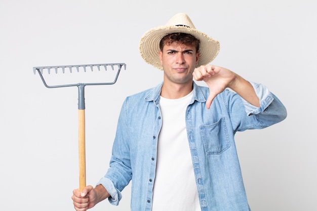 Jonge knappe man die zich boos voelt en duimen naar beneden laat zien. boer concept