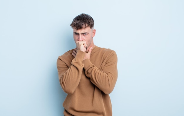 Jonge knappe man die zich ziek voelt met een zere keel en griepsymptomen, hoesten met bedekte mond