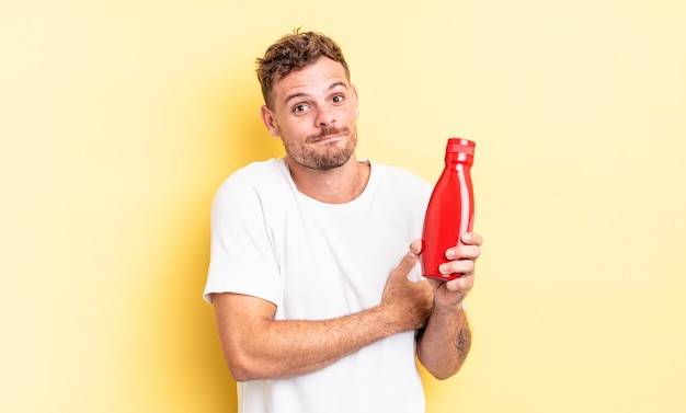 Jonge knappe man die zijn schouders ophaalt, zich verward en onzeker voelt. ketchup-concept