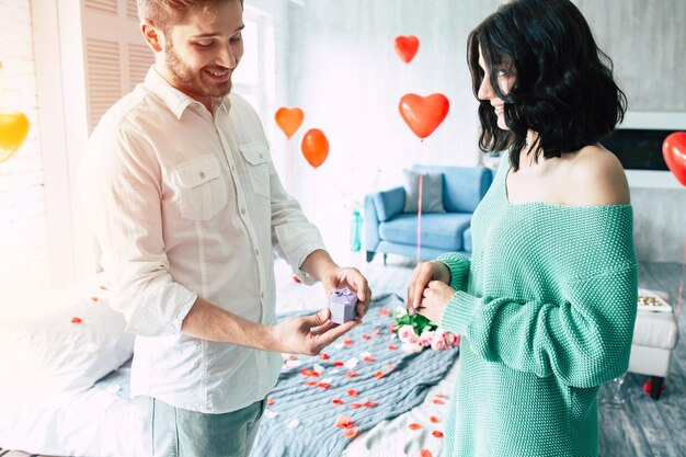 Jonge knappe man doet een voorstel aan zijn mooie vriendin om met hem te trouwen in een mooie slaapkamer met een romantische achtergrond. man en vrouw