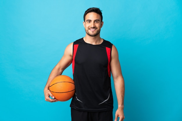 Jonge knappe man geïsoleerd op blauw basketbal spelen