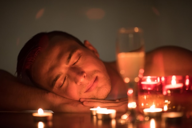 jonge knappe man geniet van ontspannen in de jacuzzi met kaarsen en champagne in luxe resort spa